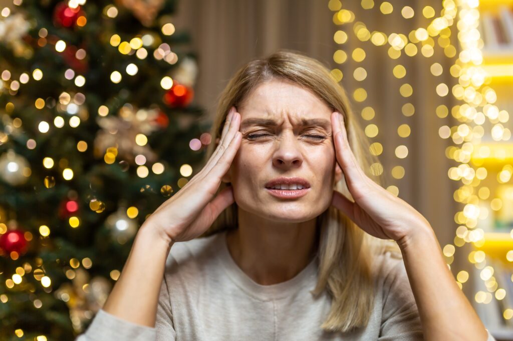 A woman grimacing in pain. She feels a headache. She is tired of preparing holidays