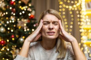 A woman grimacing in pain. She feels a headache. She is tired of preparing holidays