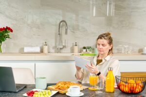 woman looking news on tablet pc during breakfast time. Addiction to gadgets.