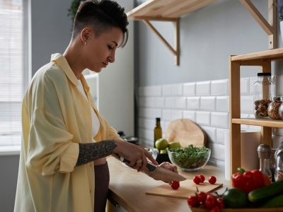 Pregnant young woman cooking healthy meal cutting vegetables in kitchen